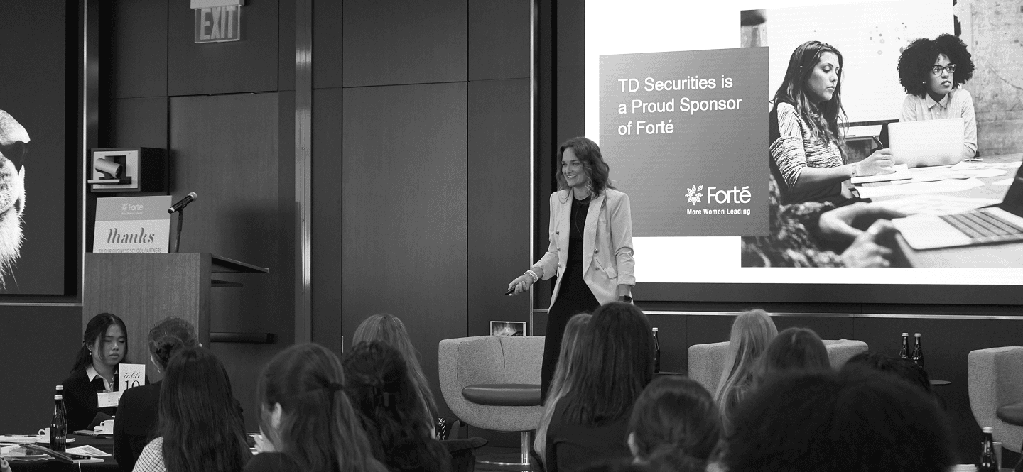 A woman smiling while presenting next to a screen